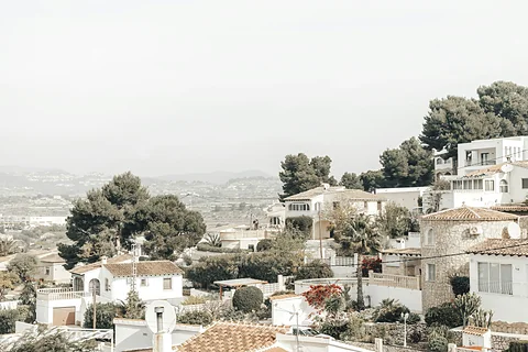 Witte villa's met terracotta daken tussen pijnbomen op een heuvel in Moraira, Costa Blanca